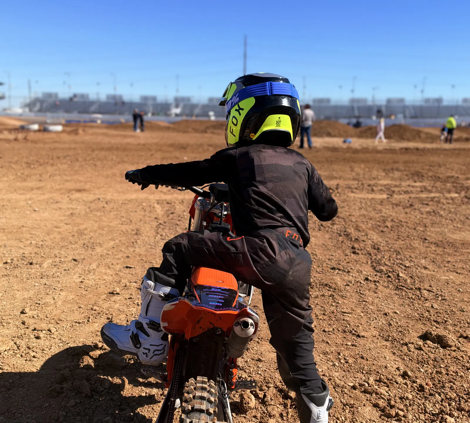 Kapakū from behind, sitting on his KTM looking down the track