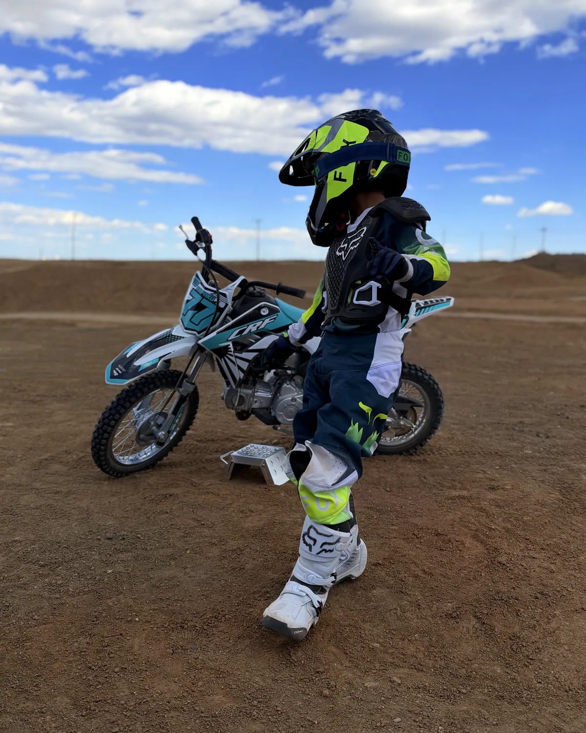 Kapakū in full gear standing next to his bike on the track